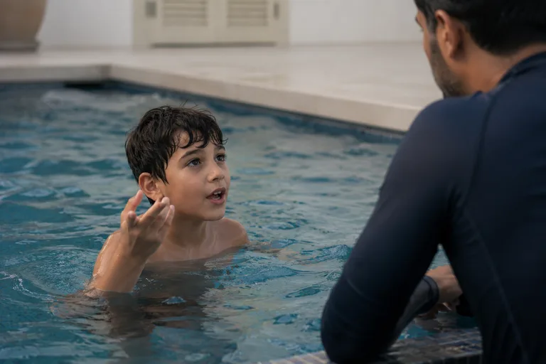 A coach listening as a child explains something in the water