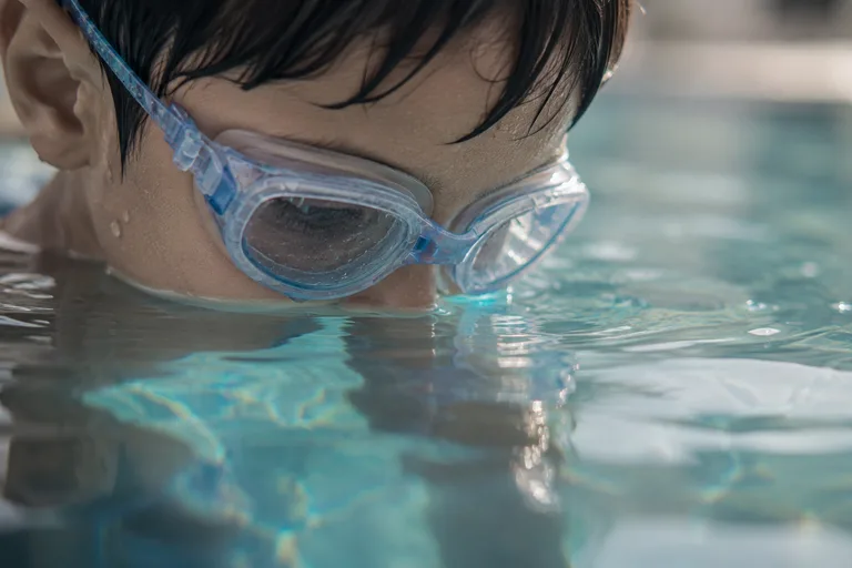 A child looking into the water through wet goggles