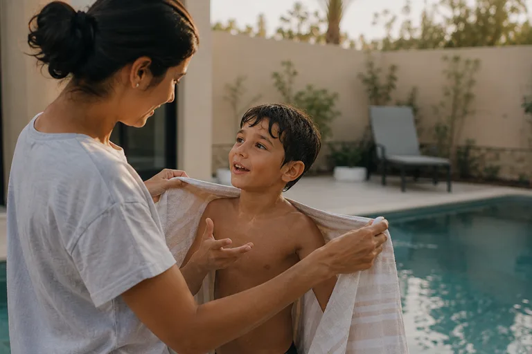 A parent wrapping a child in a towel after swimming