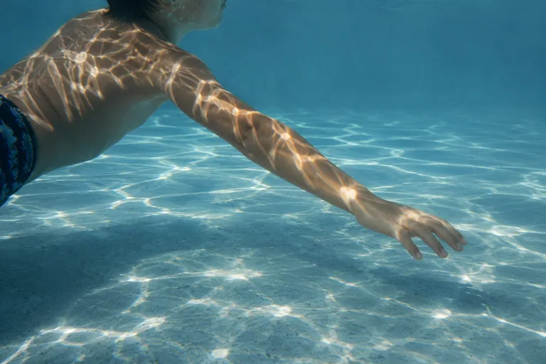 Sunlight moving across a child's arm beneath the water