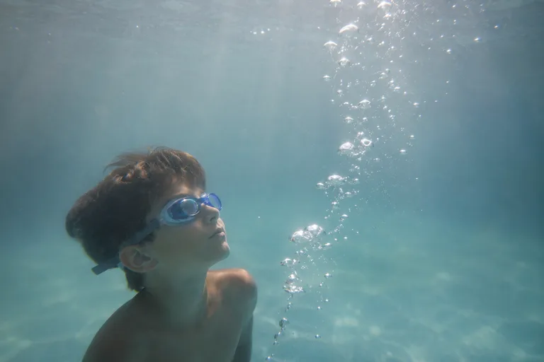 A child watching bubbles rise underwater